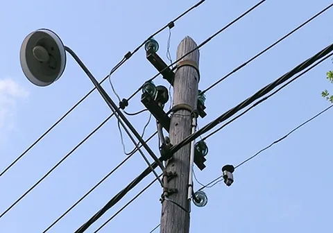 Holzmast mit Straßenleuchte und Freileitung