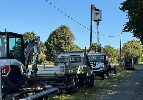 Einsatzfahrzeuge und Minibagger an einer Freileitungstrasse