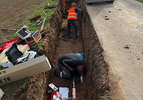 Kabelmontage in einem langen Graben am Feldweg