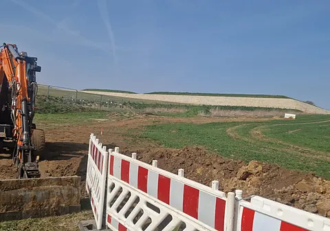 Absperrschranken an einer Feldbaustelle mit Bagger