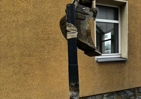 Minibagger bei Erdarbeiten an einer Hauswand