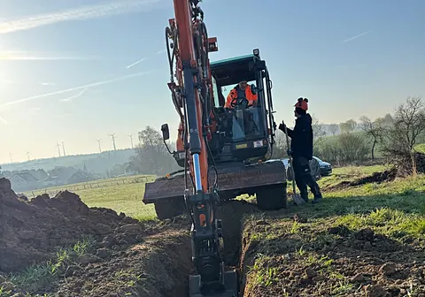 Mobilbagger beim Grabenaushub im Feld