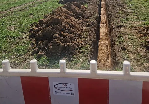 Kabeltrasse im Feld hinter Absperrschranken der SB Straßen & Tiefbau