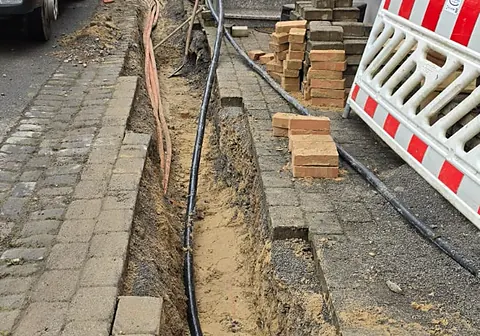 Kabelgraben in einem gepflasterten Gehweg vor Wohnhäusern