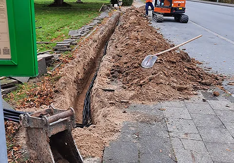 Leitungsgraben neben einem gepflasterten Gehweg